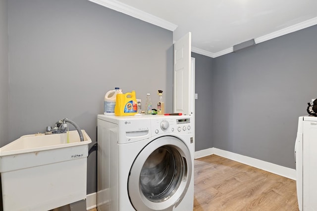 washroom featuring crown molding, washer / clothes dryer, light hardwood / wood-style floors, and sink