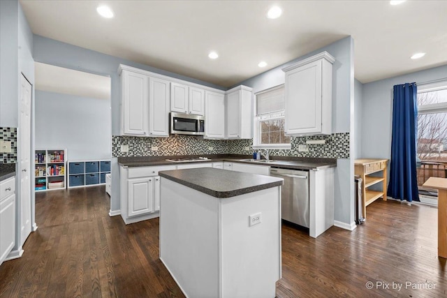 kitchen with a kitchen island, white cabinetry, appliances with stainless steel finishes, and dark hardwood / wood-style floors