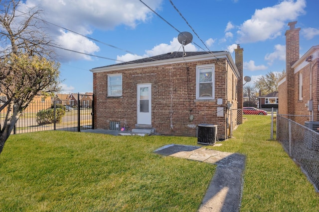 rear view of property with central AC and a lawn