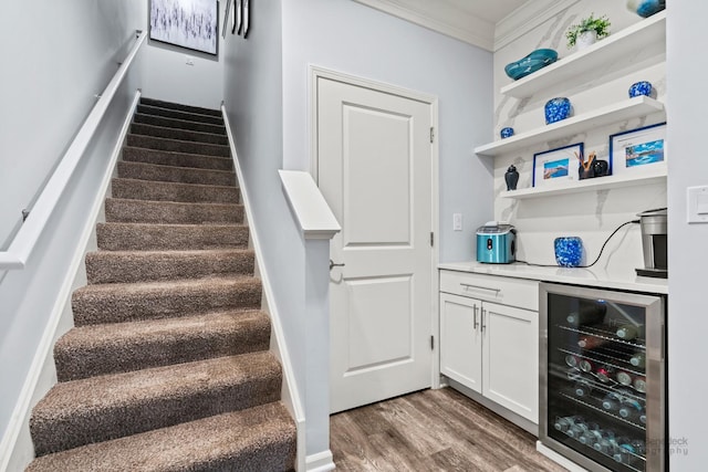 bar with crown molding, hardwood / wood-style flooring, white cabinets, and beverage cooler