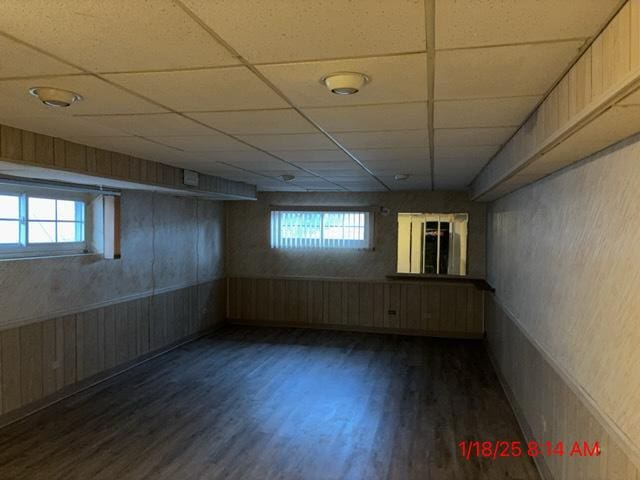 basement with plenty of natural light, dark wood-type flooring, and a paneled ceiling