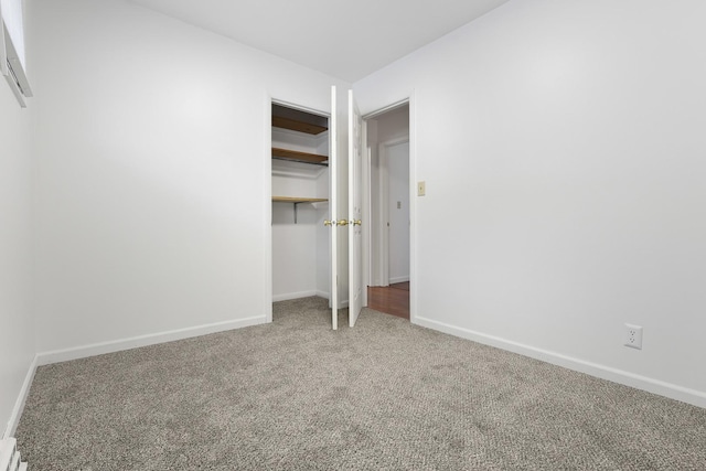 unfurnished bedroom with baseboard heating, a closet, and carpet