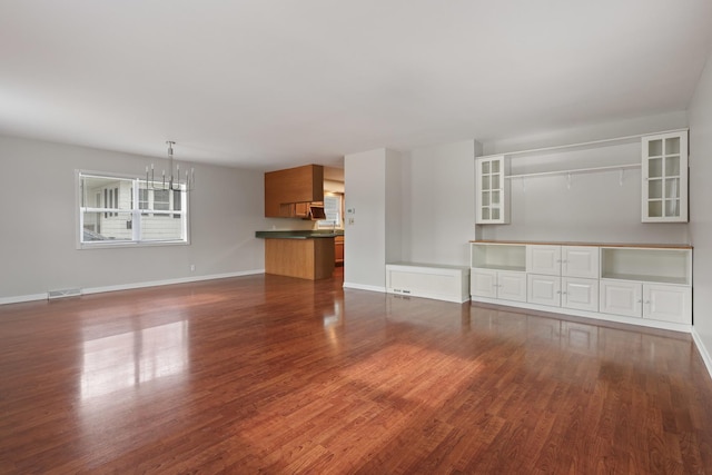 unfurnished living room featuring dark wood-type flooring and a chandelier