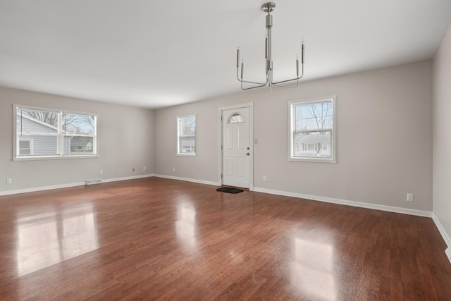 interior space featuring a healthy amount of sunlight, dark hardwood / wood-style floors, and a chandelier