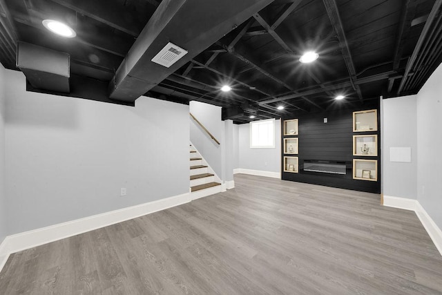 basement featuring wood-type flooring and a large fireplace