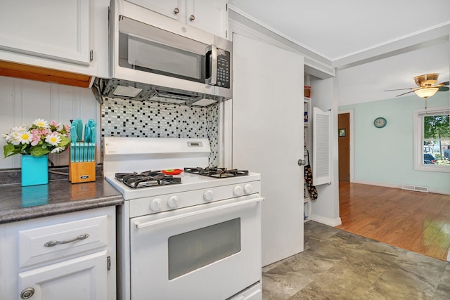 kitchen with ceiling fan, ornamental molding, gas range gas stove, and white cabinets