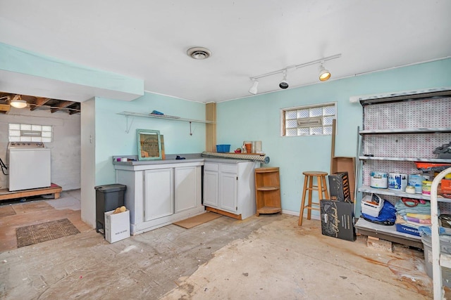 kitchen featuring washer / dryer and white cabinets