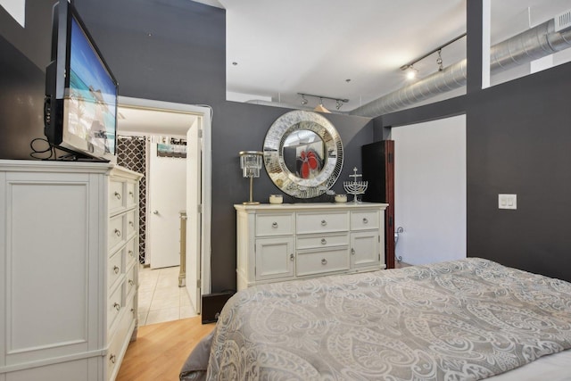 bedroom with rail lighting and light wood-type flooring