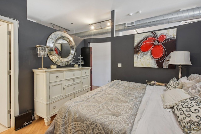 bedroom featuring track lighting and light hardwood / wood-style floors