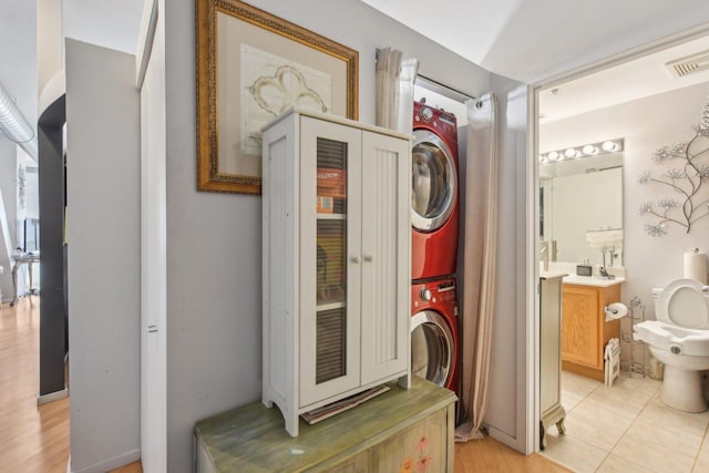 laundry area with light tile patterned floors and stacked washer and clothes dryer