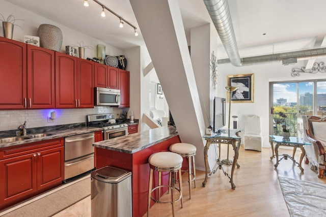 kitchen featuring appliances with stainless steel finishes, sink, a breakfast bar, and decorative backsplash