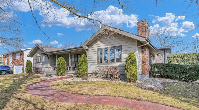 view of front of property featuring a garage, a front lawn, and covered porch