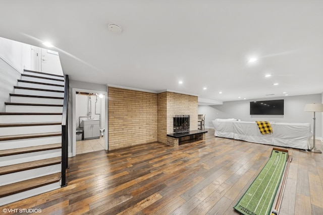 unfurnished living room featuring hardwood / wood-style flooring and a brick fireplace