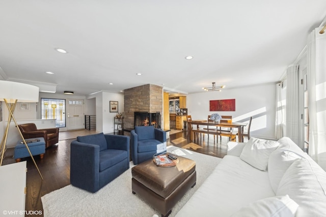 living room with crown molding, a stone fireplace, and dark hardwood / wood-style floors