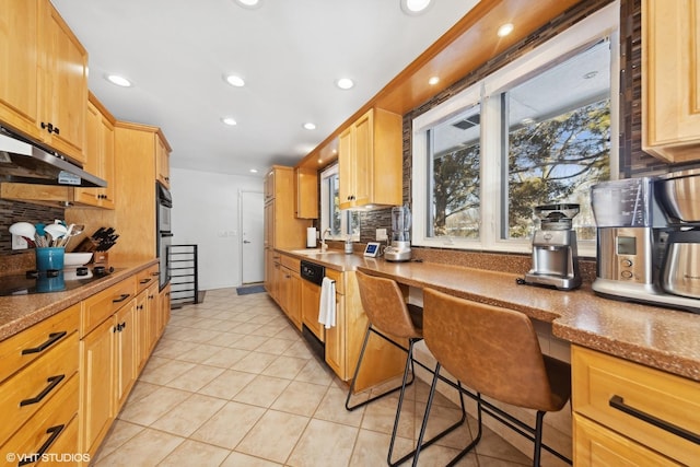 kitchen featuring a kitchen bar, sink, built in desk, light stone countertops, and black appliances