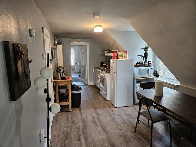 kitchen with vaulted ceiling, white appliances, and light hardwood / wood-style flooring