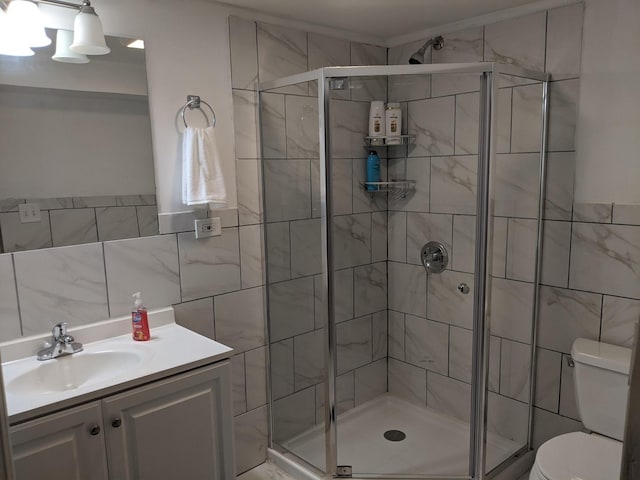 bathroom featuring vanity, toilet, a shower with door, and tile walls