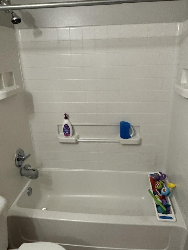 bathroom with tiled shower / bath combo and toilet