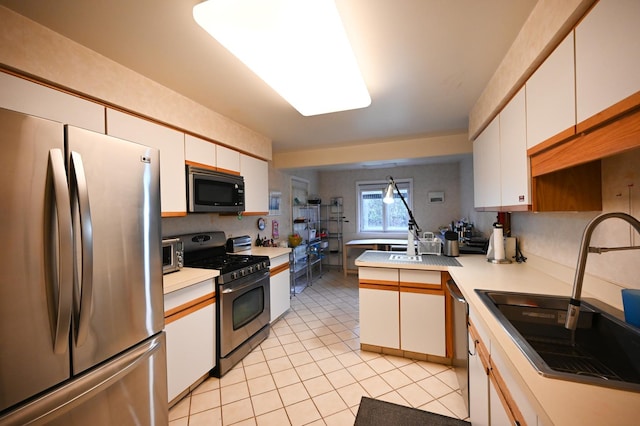 kitchen featuring sink, light tile patterned floors, stainless steel appliances, and white cabinets