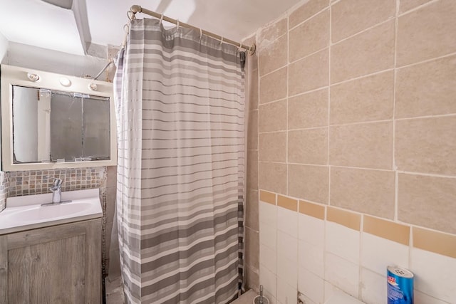 bathroom with a shower with curtain, vanity, tile walls, and backsplash