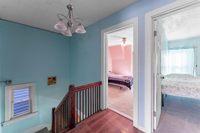 corridor featuring an inviting chandelier, hardwood / wood-style floors, and a textured ceiling