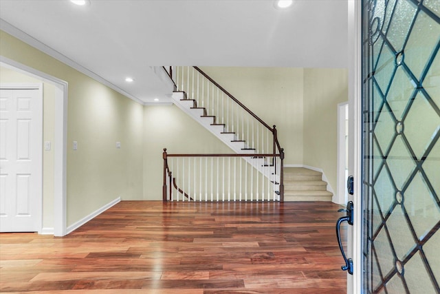 foyer entrance featuring baseboards, ornamental molding, wood finished floors, stairs, and recessed lighting