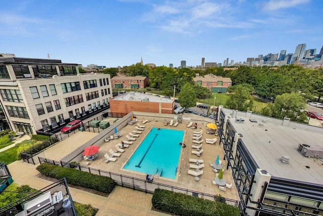 view of swimming pool with fence and a city view