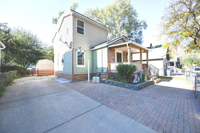 back of house with a shed, covered porch, and a patio