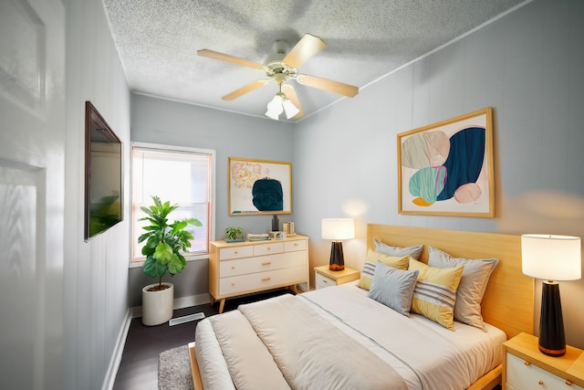 bedroom featuring dark wood-type flooring, ceiling fan, and a textured ceiling