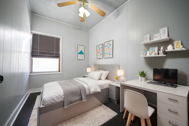 bedroom with ceiling fan, a textured ceiling, and dark hardwood / wood-style flooring