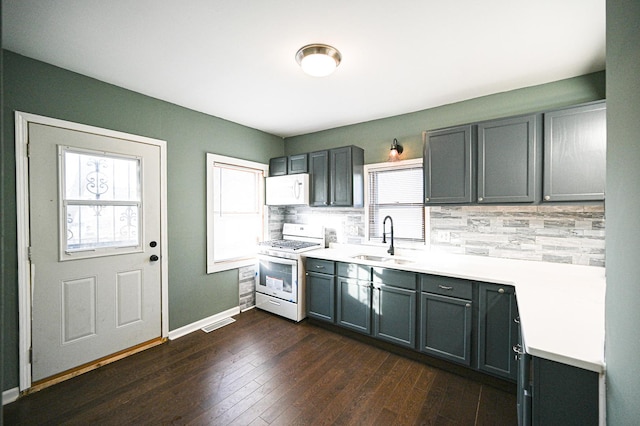 kitchen featuring gray cabinets, tasteful backsplash, sink, dark hardwood / wood-style flooring, and white appliances