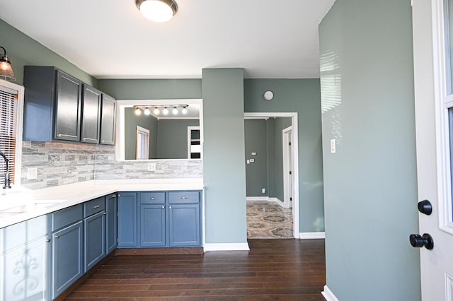 kitchen with tasteful backsplash, sink, dark wood-type flooring, and blue cabinets