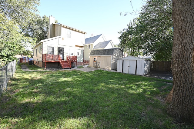 rear view of house featuring a storage shed, a lawn, and a wooden deck