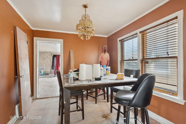 dining space featuring an inviting chandelier, crown molding, and light wood-type flooring