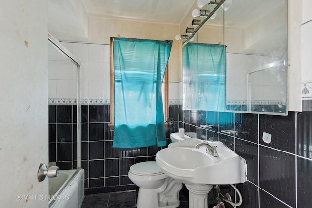 bathroom featuring shower / washtub combination, toilet, tile patterned flooring, and tile walls