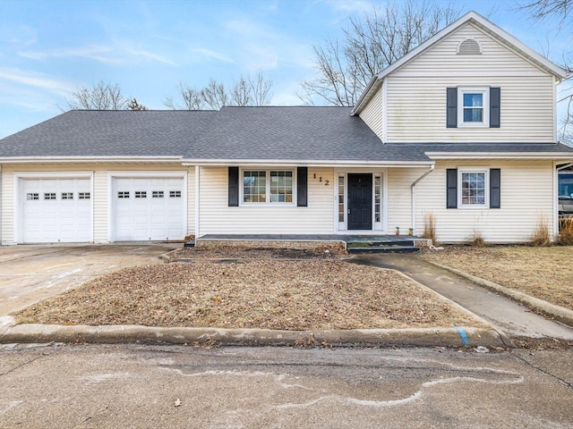 traditional-style home featuring driveway, an attached garage, and roof with shingles