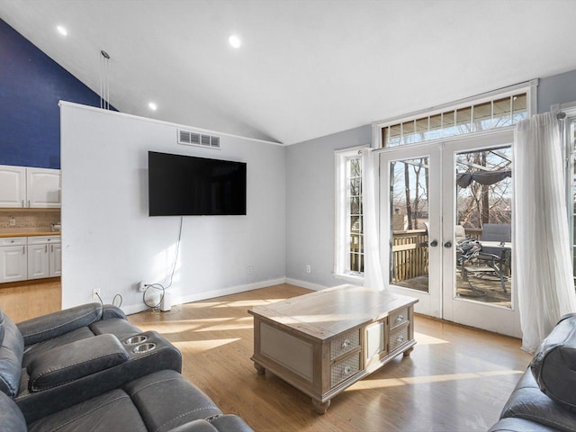 living room with visible vents, high vaulted ceiling, french doors, light wood-style floors, and baseboards