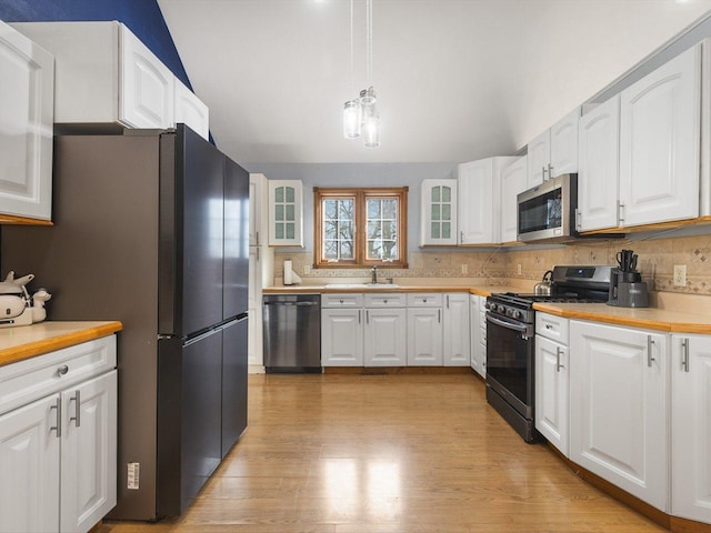 kitchen featuring a sink, glass insert cabinets, appliances with stainless steel finishes, and decorative backsplash