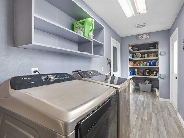 washroom featuring baseboards, light wood-style flooring, laundry area, and washing machine and clothes dryer