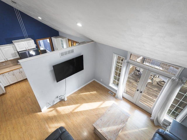 unfurnished living room featuring vaulted ceiling, recessed lighting, light wood-style floors, and visible vents