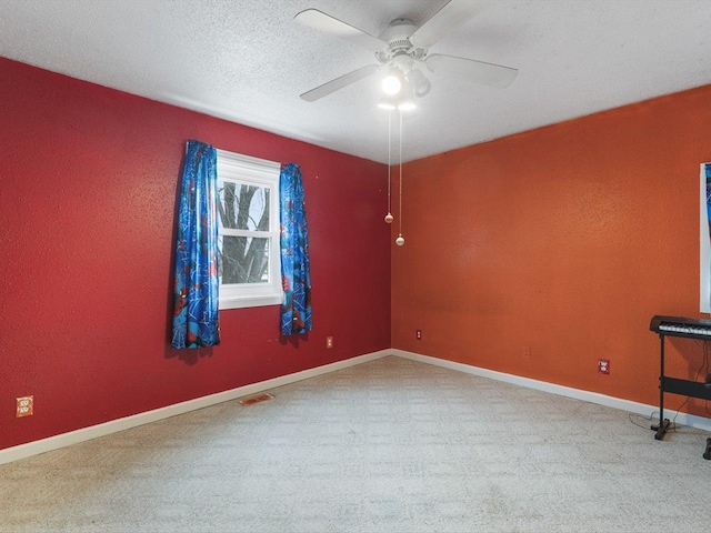 spare room with a ceiling fan, baseboards, visible vents, carpet floors, and a textured ceiling