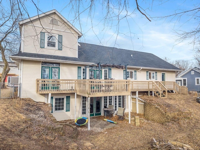 rear view of house featuring stairway, a wooden deck, fence, and a shingled roof