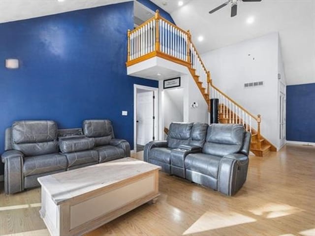 living room with stairway, wood finished floors, visible vents, high vaulted ceiling, and ceiling fan