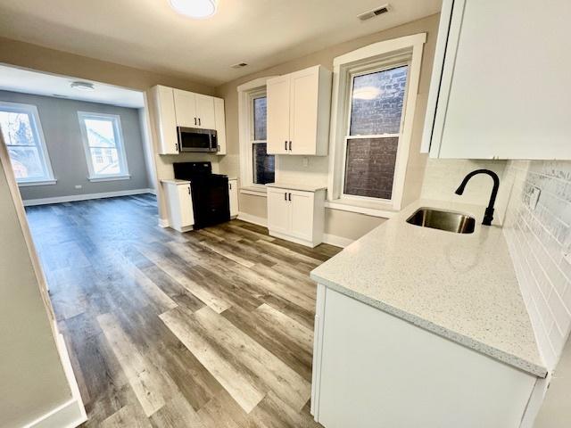 kitchen featuring sink, backsplash, white cabinets, range, and light stone counters