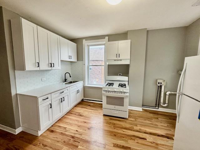 kitchen featuring white cabinetry, sink, white appliances, and light hardwood / wood-style flooring