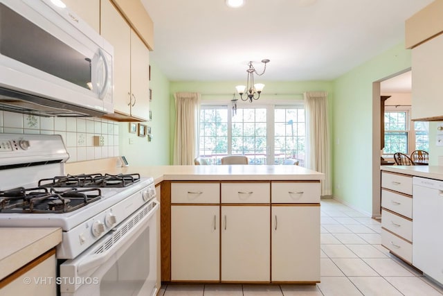 kitchen with decorative backsplash, hanging light fixtures, kitchen peninsula, plenty of natural light, and white appliances