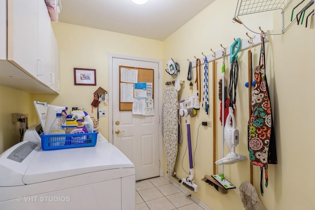 clothes washing area with washer and dryer, cabinets, and light tile patterned flooring