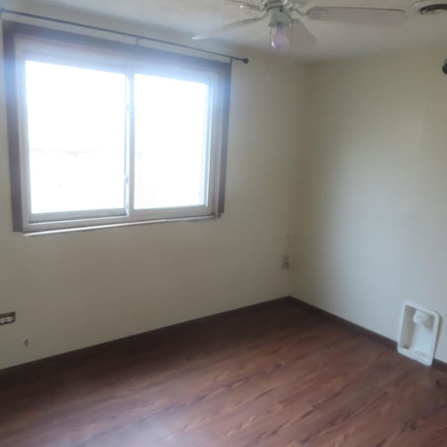 spare room with dark hardwood / wood-style floors and ceiling fan