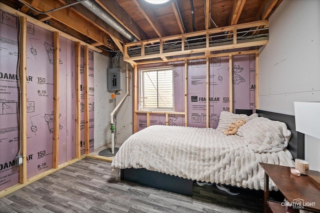 bedroom with electric panel and wood finished floors