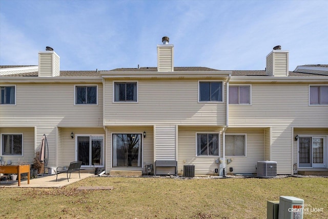 back of house featuring a patio, central AC unit, a lawn, and a chimney